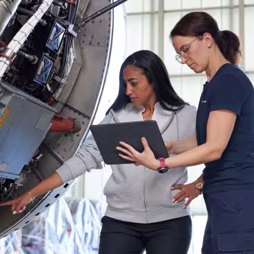 two women with tablet in front of an engine