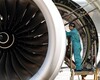 Aircraft engine maintenance technician inspecting a jet engine on a maintenance platform.